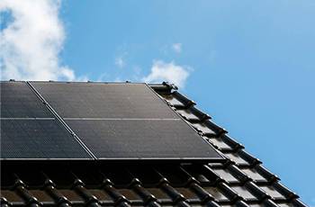 Rechte Seite eines Daches mit schwarzen Dachpfannen und dunklen Solarmodulen - enivon